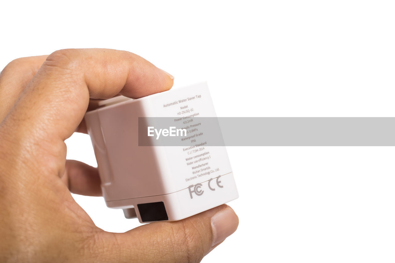 CLOSE-UP OF PERSON HAND HOLDING PAPER AGAINST WHITE BACKGROUND