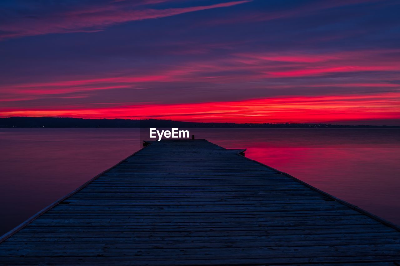 Pier over lake against sky during sunset