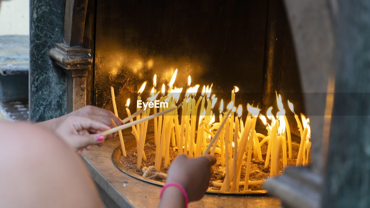 burning, hand, fire, flame, heat, one person, yellow, candle, religion, belief, lighting, spirituality, holding, selective focus, adult, place of worship, nature, temple - building, tradition, close-up, indoors, igniting, personal perspective, praying, glowing
