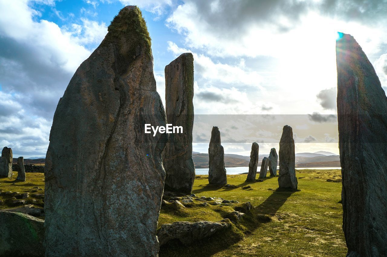 Rocks on field at hebrides against sky