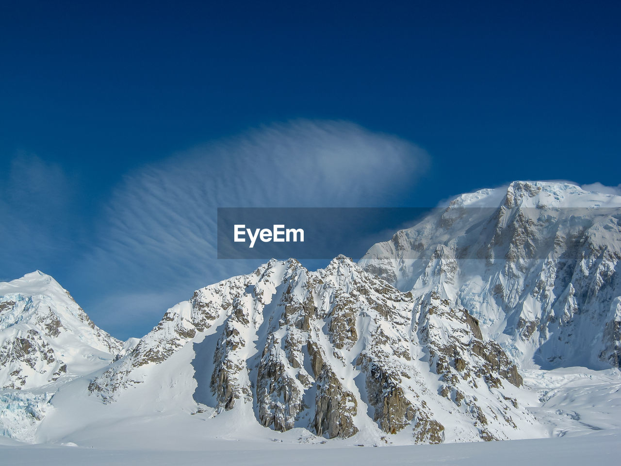 Scenic view of snowcapped mountains against blue sky