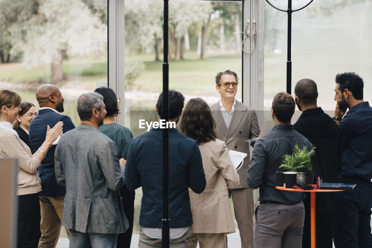 Mature entrepreneur talking to colleagues in office workshop