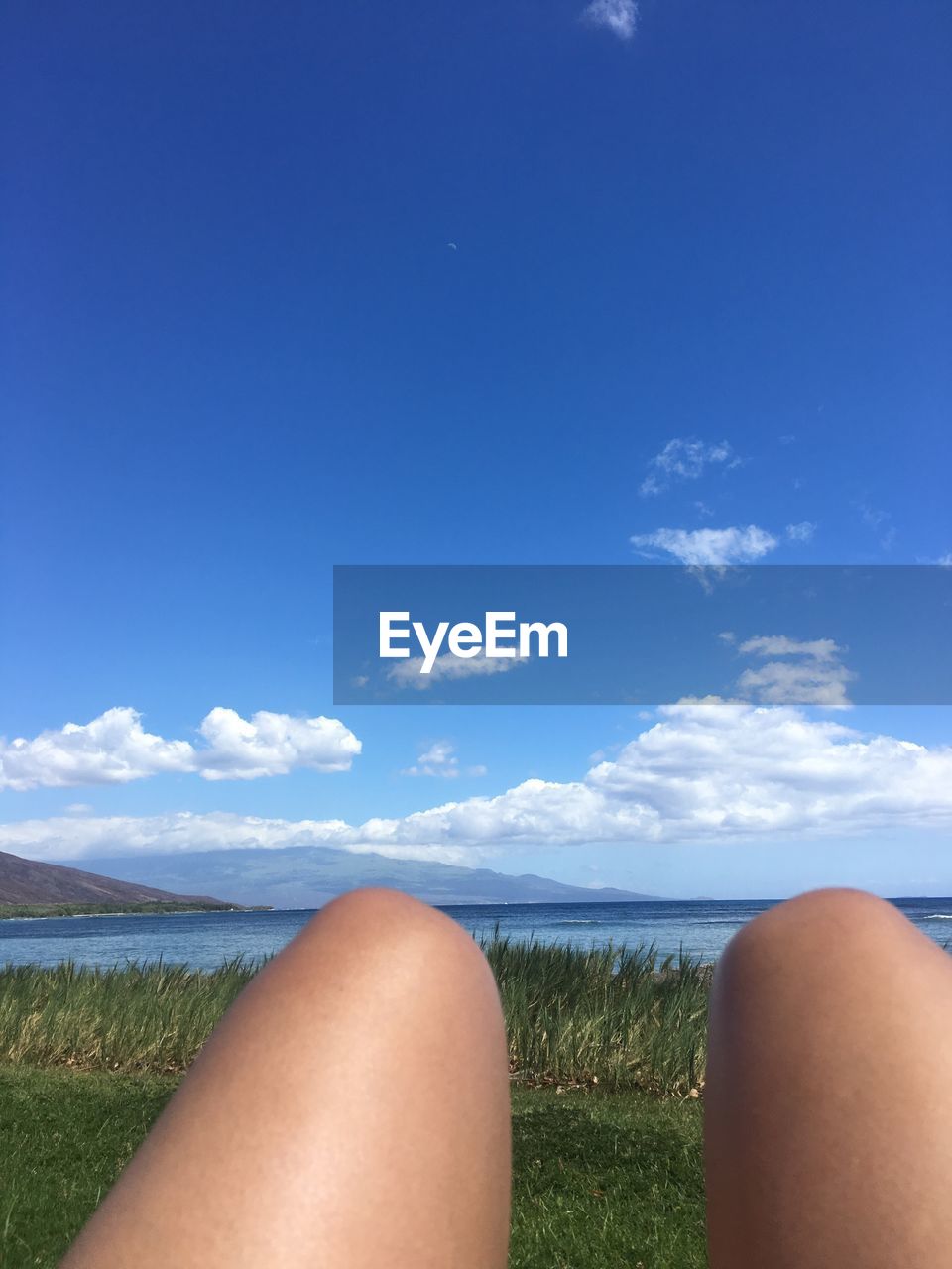 Midsection of woman relaxing at beach against sky