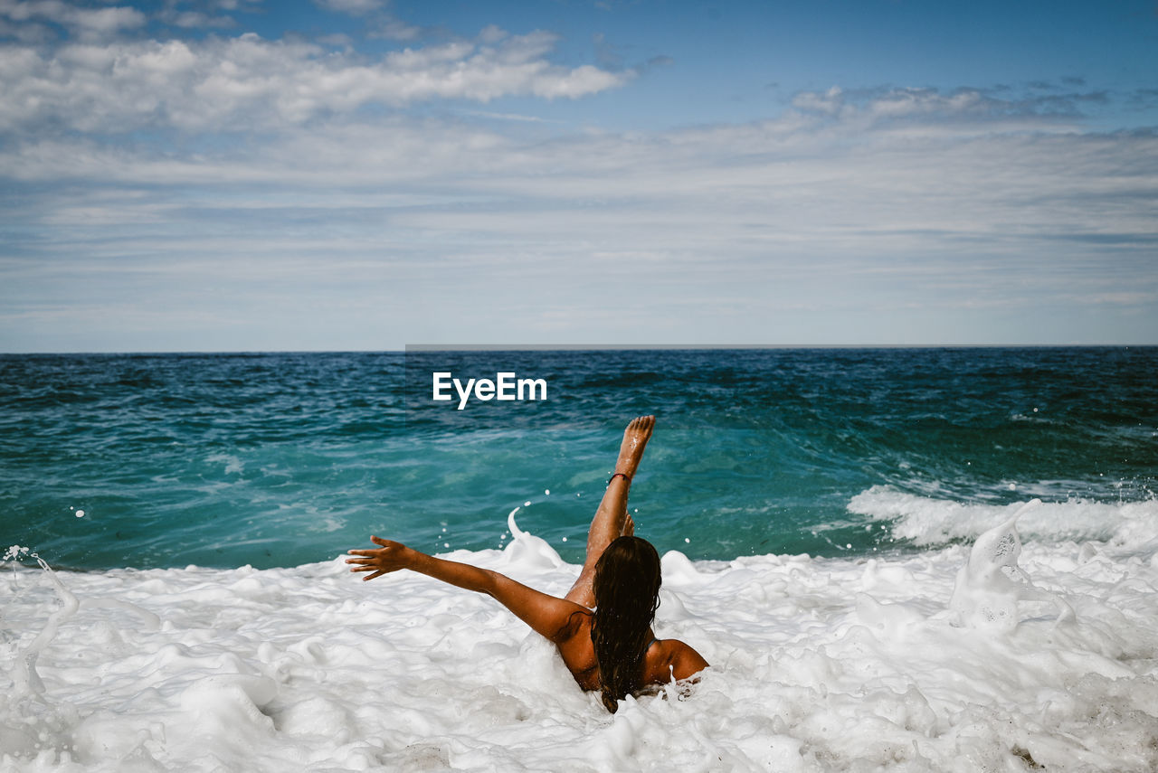 Rear view of woman in sea against sky