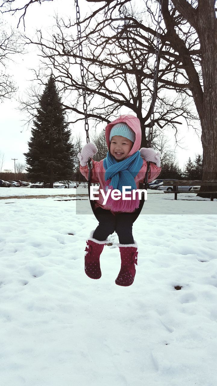 Cute girl on swing in park during winter