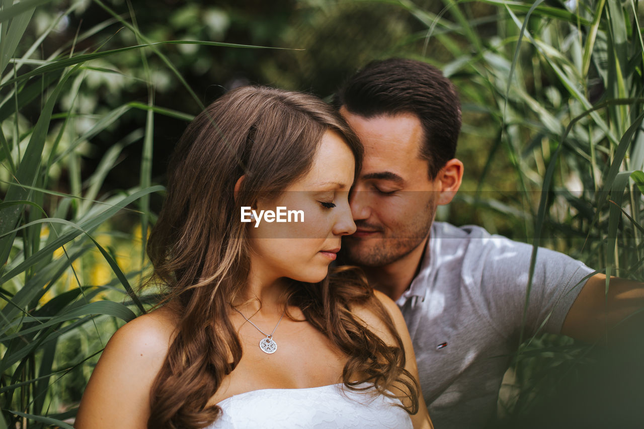 Husband and wife sitting against plants