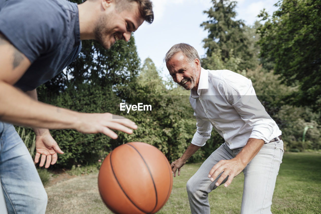 Playful father and son with basketball in backyard