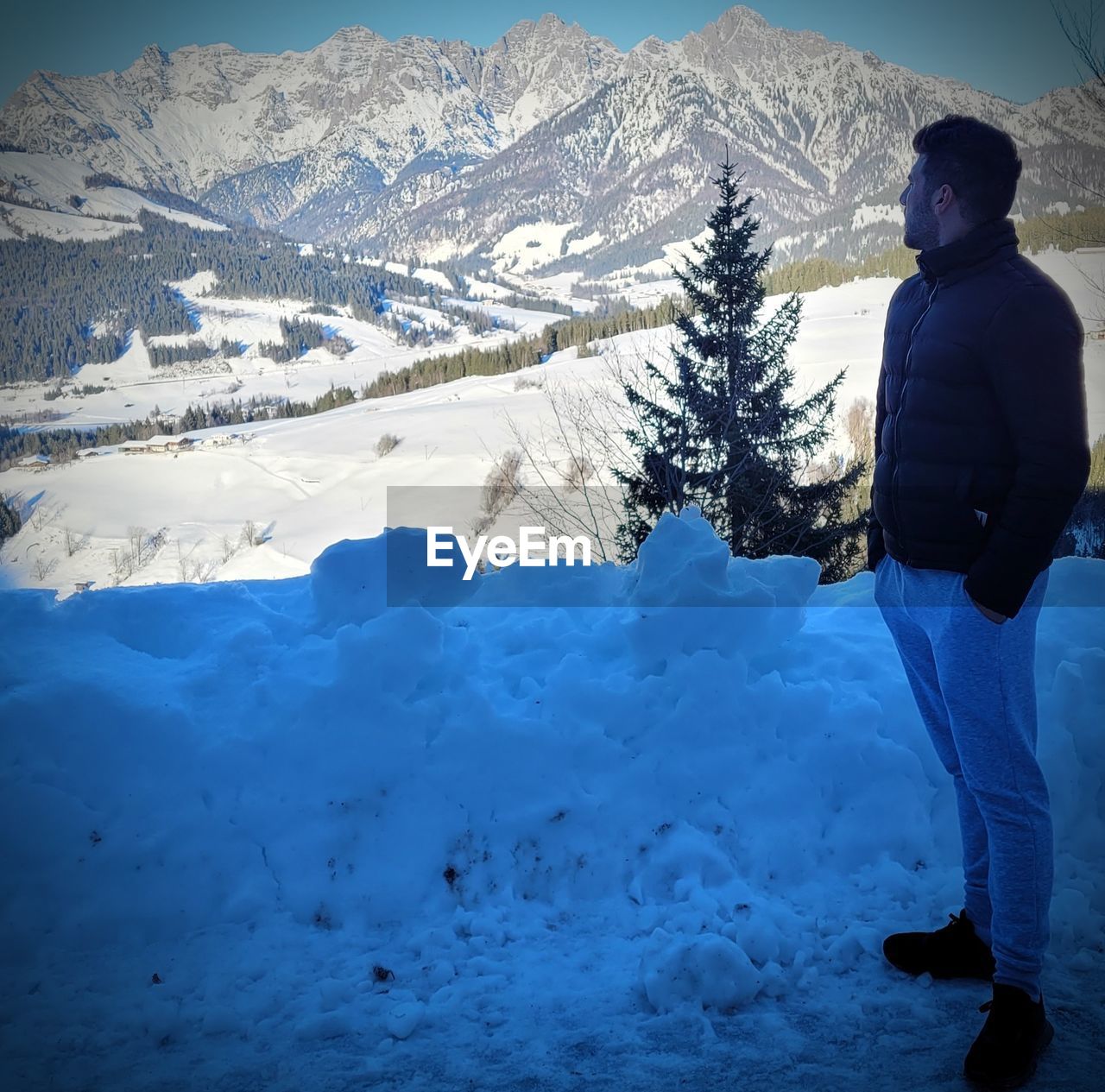 snow, cold temperature, winter, mountain, one person, beauty in nature, scenics - nature, leisure activity, nature, footwear, blue, mountain range, environment, landscape, warm clothing, rear view, snowcapped mountain, adult, men, standing, holiday, clothing, vacation, adventure, frozen, non-urban scene, trip, tranquil scene, day, full length, travel, land, lifestyles, tranquility, sports, sky, ice, person, travel destinations, winter sports, outdoors, freezing, skiing, white, summit, hiking, tree, activity, plant, remote, exploration, extreme terrain