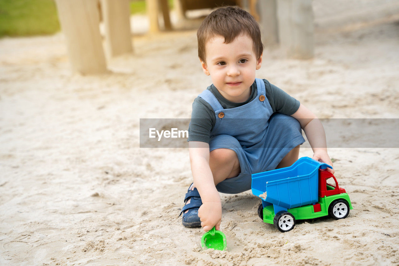 Little cute toddler boy 2.5 years old plays in the sandbox on a sunny summer day.