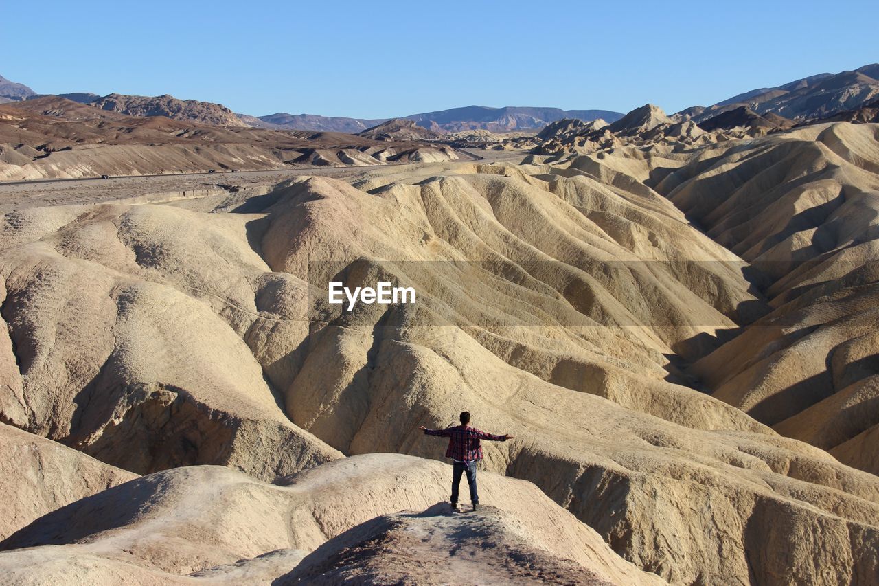 Rear view of man standing on rocky mountain