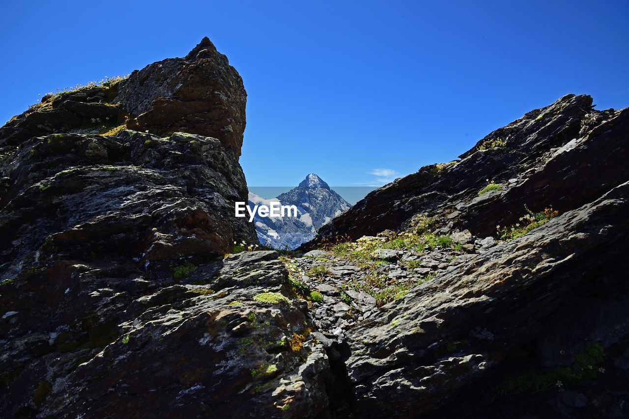 LOW ANGLE VIEW OF ROCKS AGAINST BLUE SKY