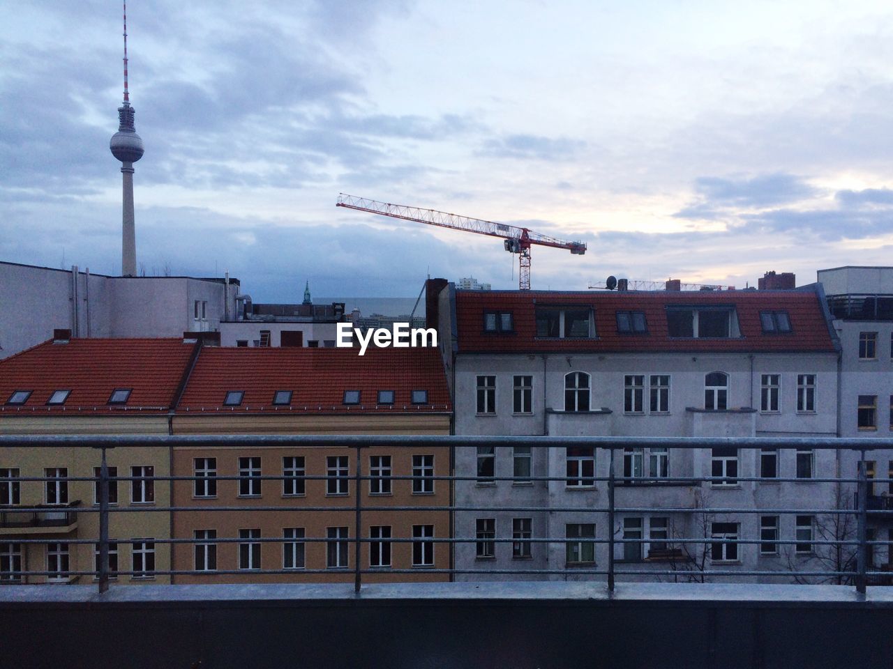 Fernsehturm tower and buildings against sky at dusk