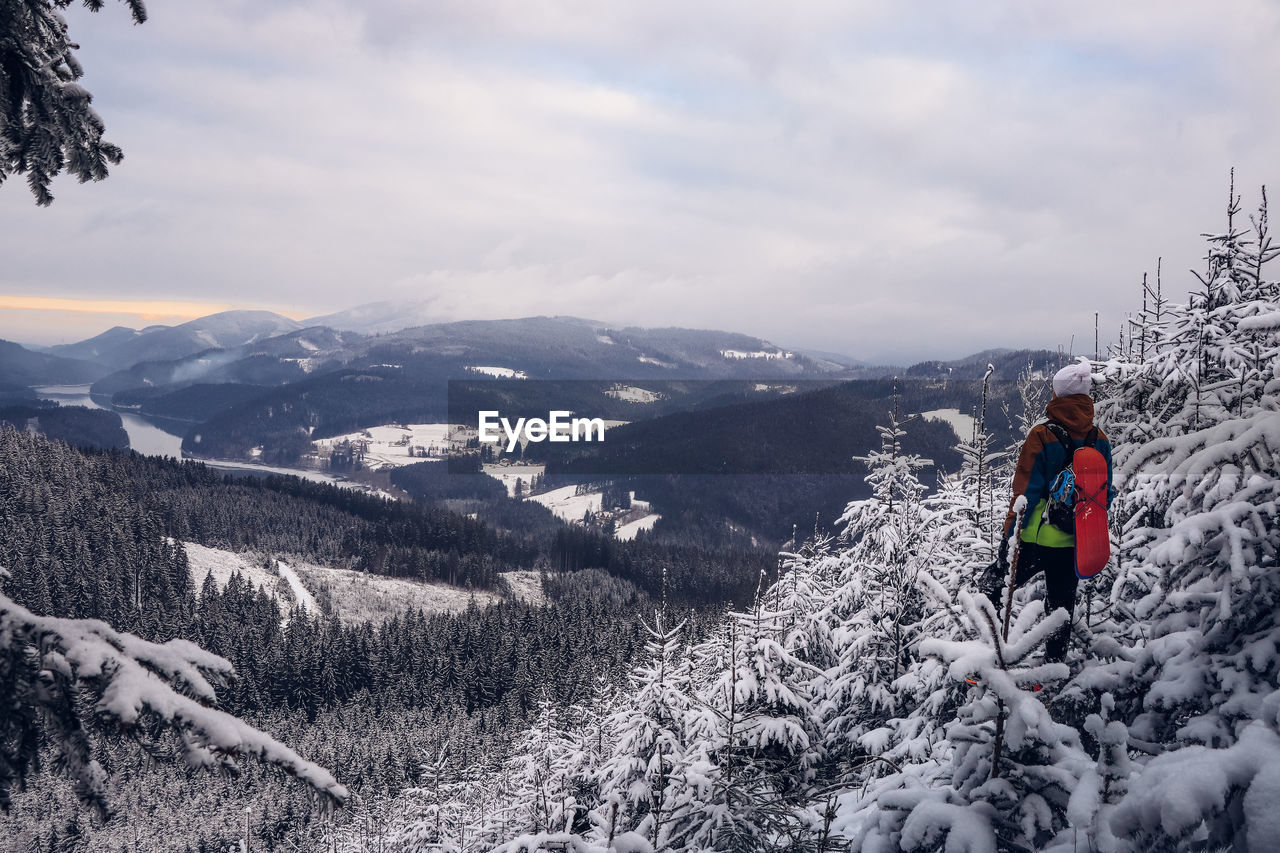 Candid portrait of man wearing winter clothes overlooking the snowy area of beskydy mountains.