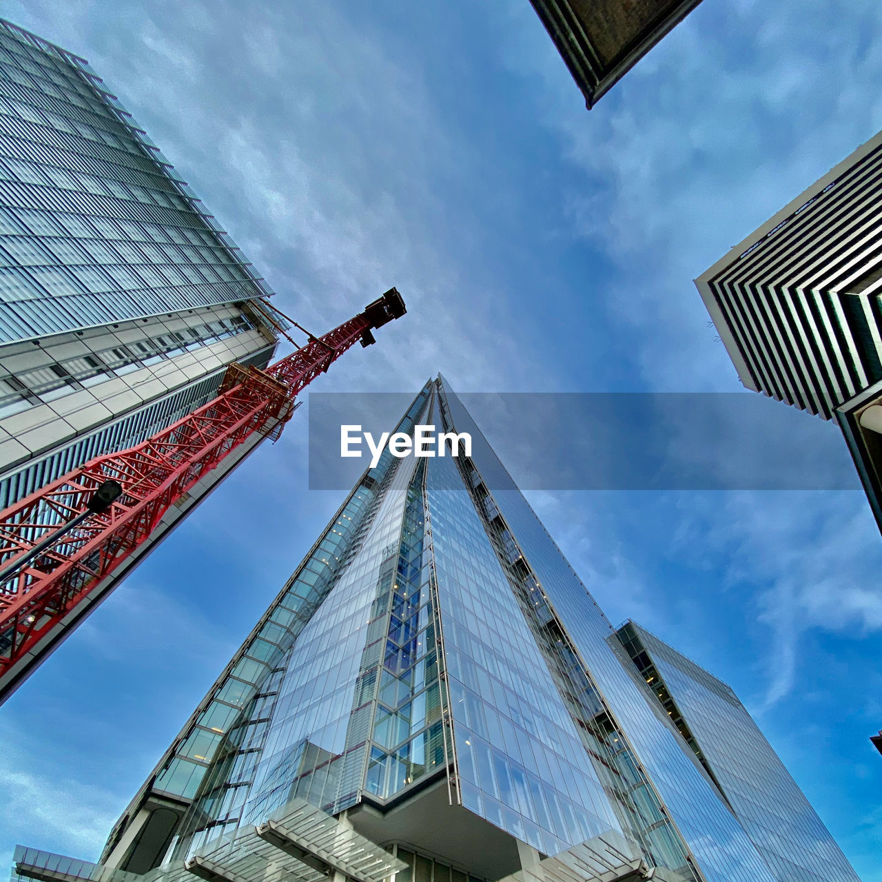 Low angle view of shard and surrounding buildings against cloudy sky in london