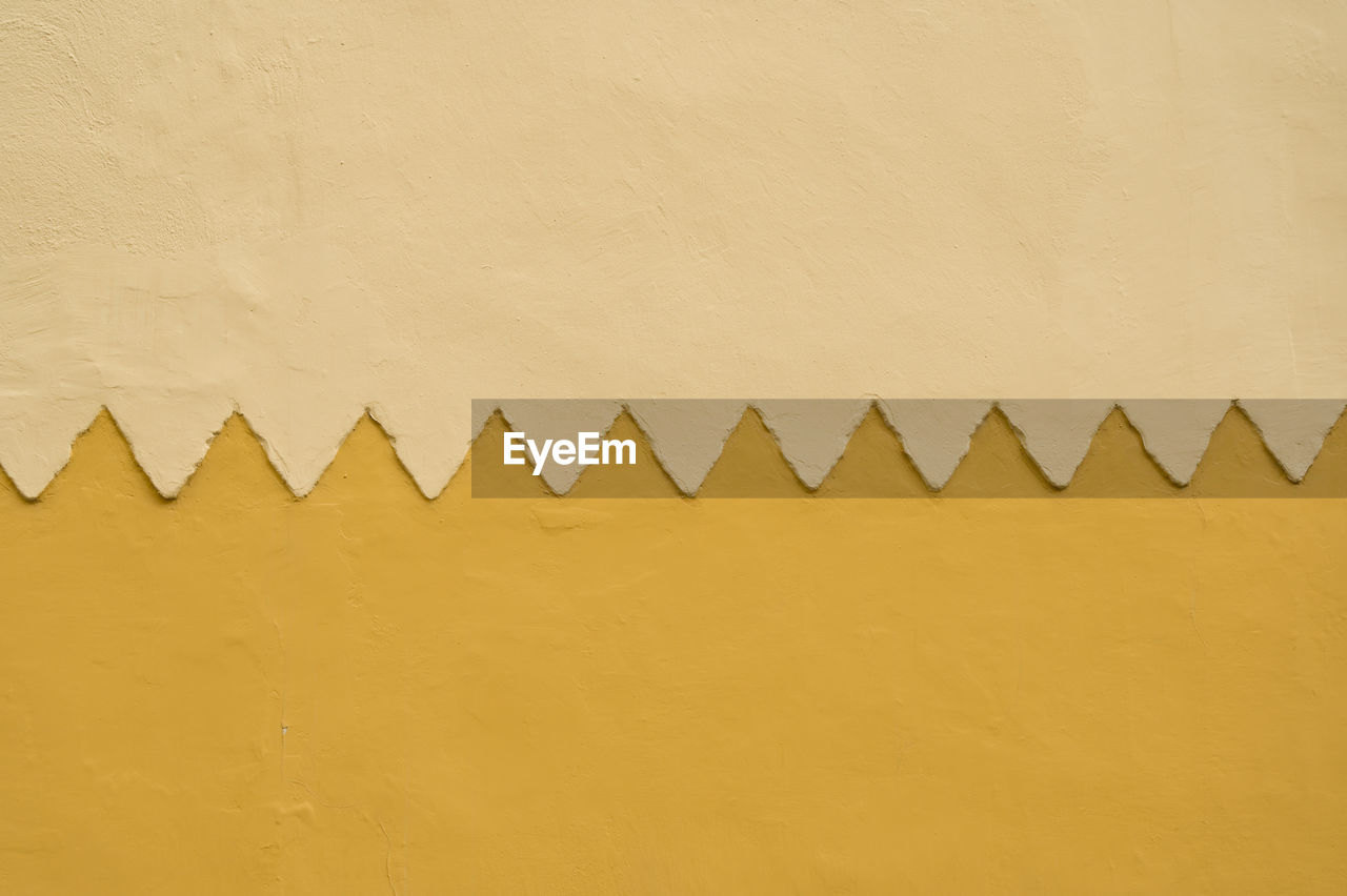 Close-up of simmetric wall pattern with yellow ocre colors