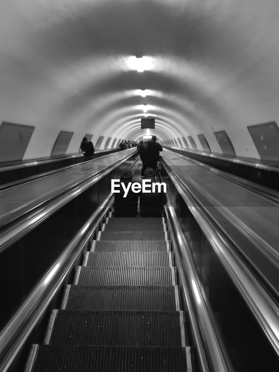 Rear view of men sitting on escalator at subway station
