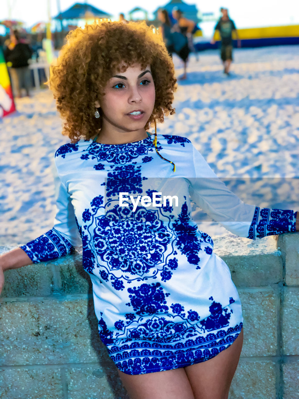 Young woman standing against wall at beach