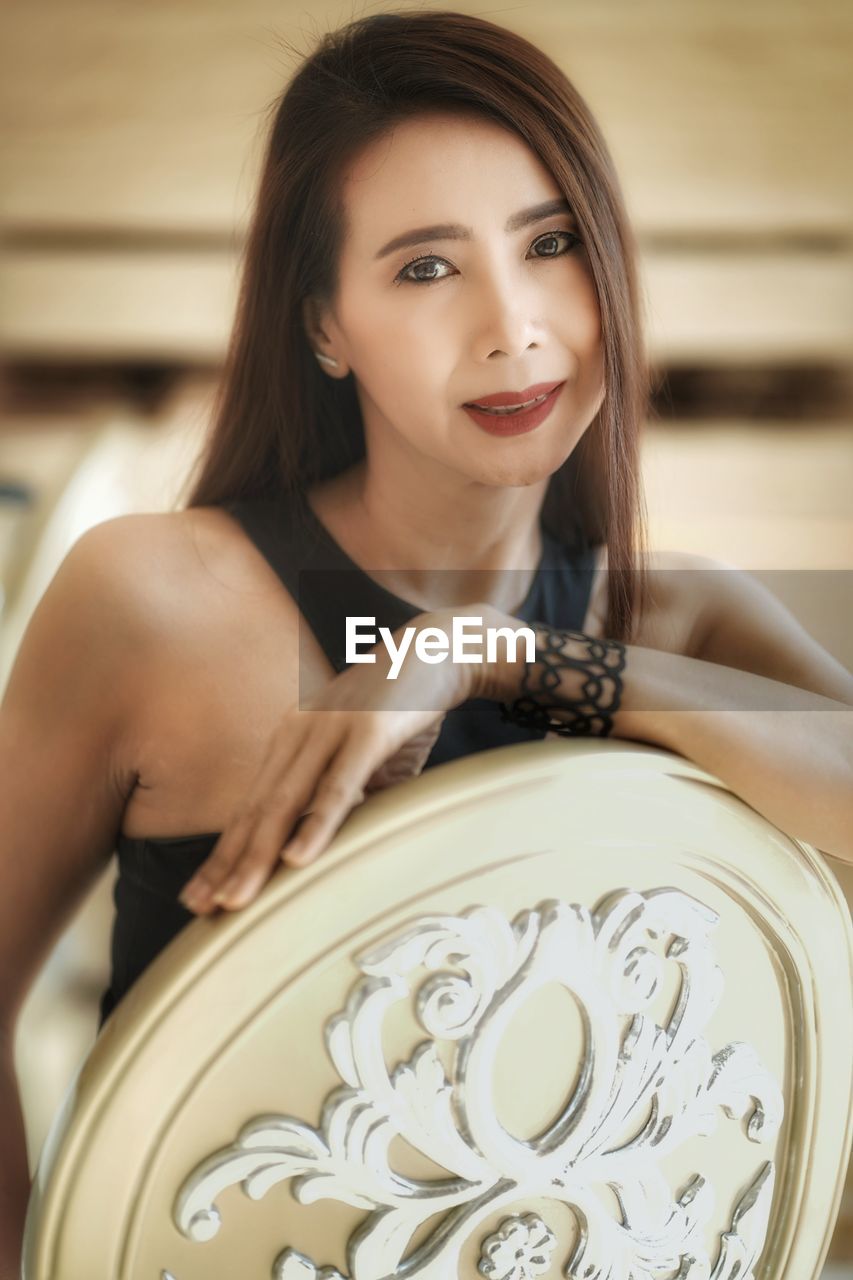 Portrait of smiling woman looking away while sitting on seat