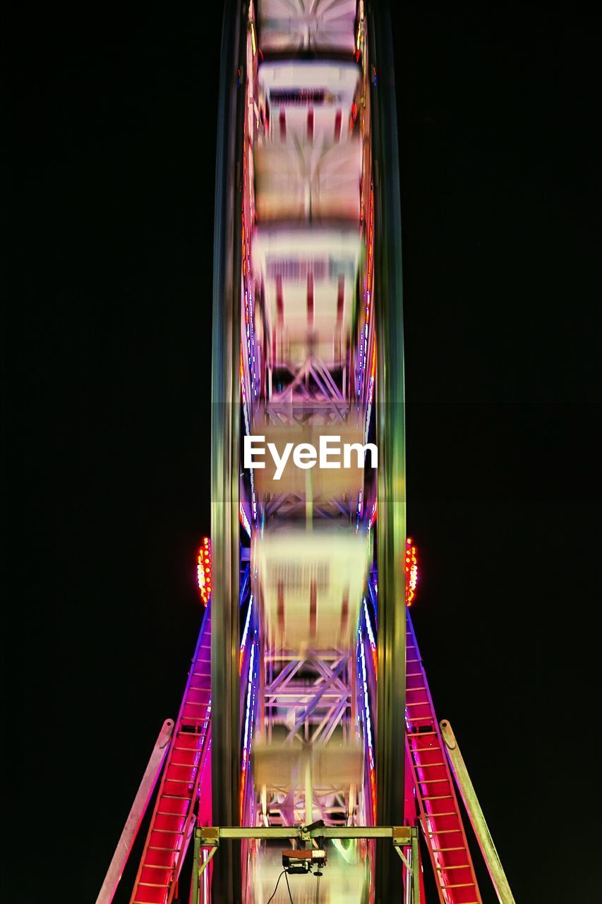 Blurred motion of illuminated ferris wheel against sky at night