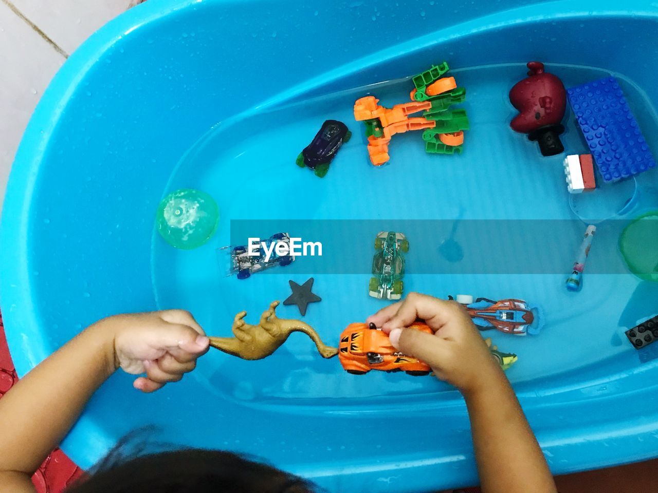 High angle view cropped hands of boy playing with toys in tub