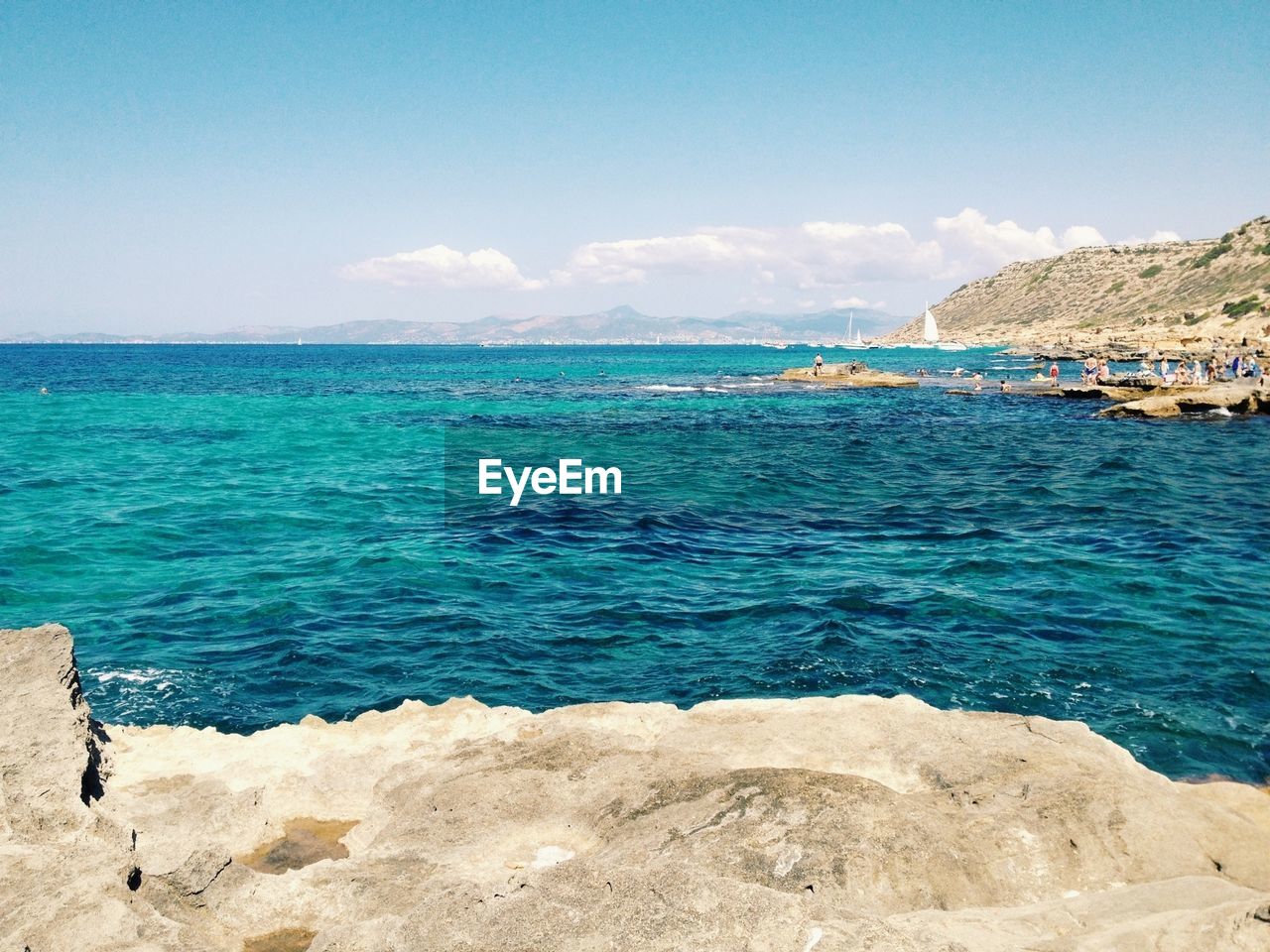 View of calm blue sea with people in distance