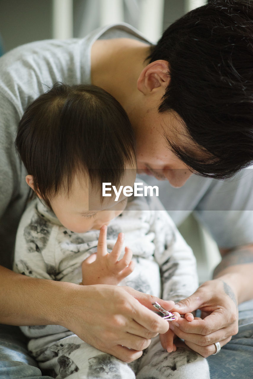 Close-up of father clipping baby's fingernails