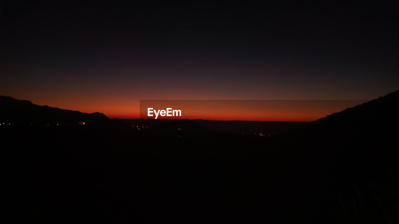 SCENIC VIEW OF SILHOUETTE LANDSCAPE AGAINST SKY AT SUNSET