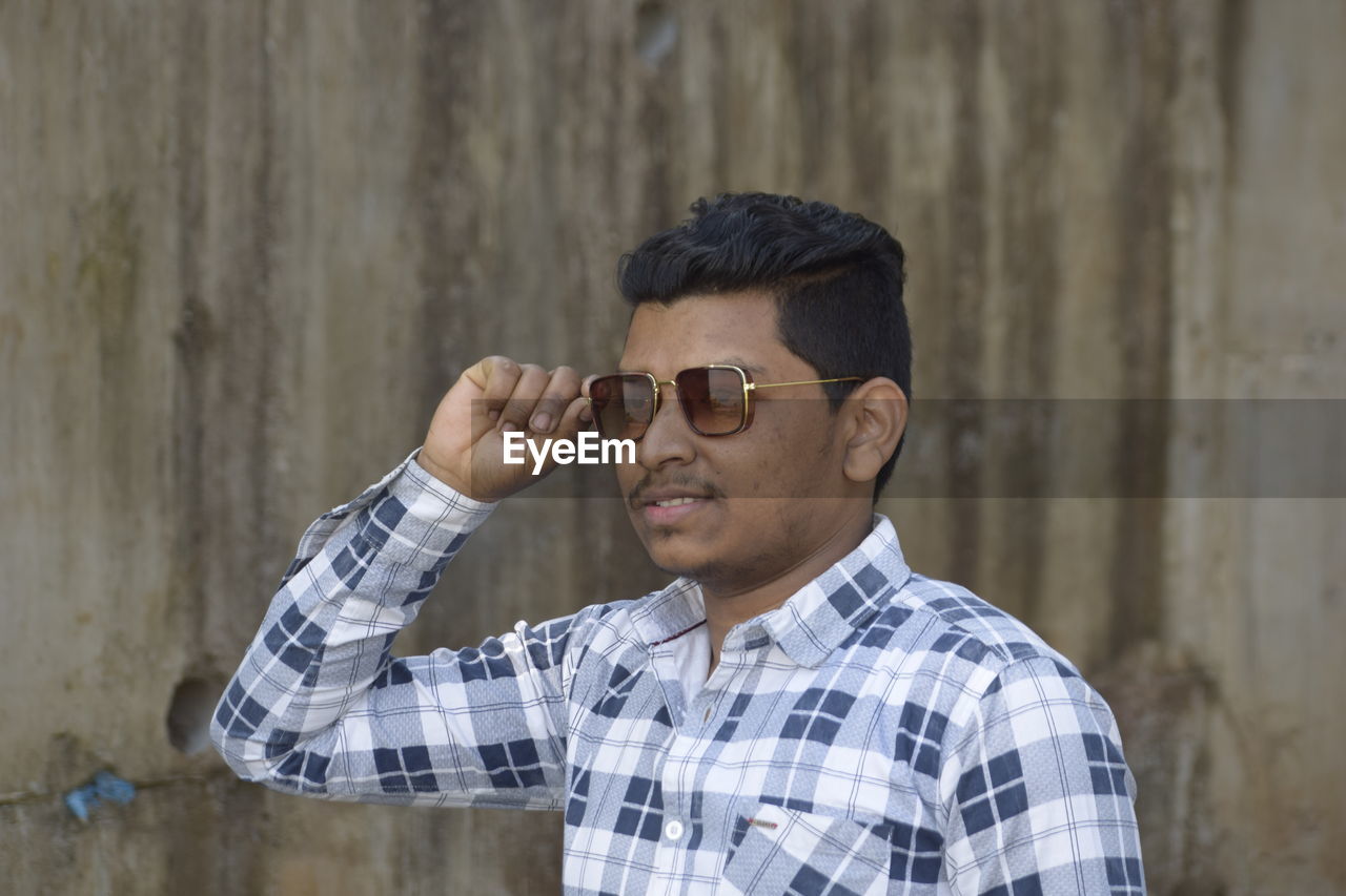 Portrait of young man wearing sunglasses standing outdoors