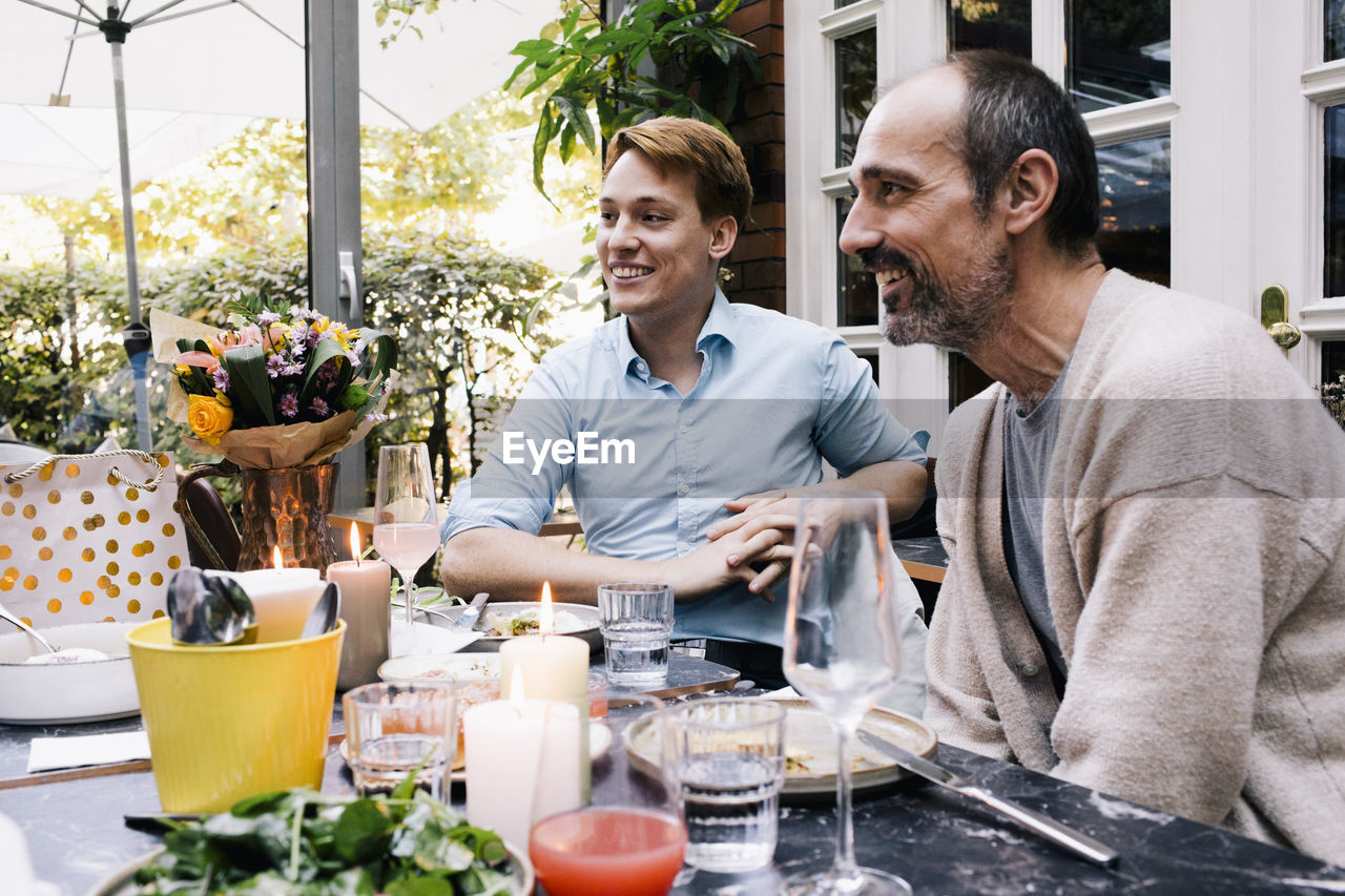 Happy parent sitting with son at restaurant during party