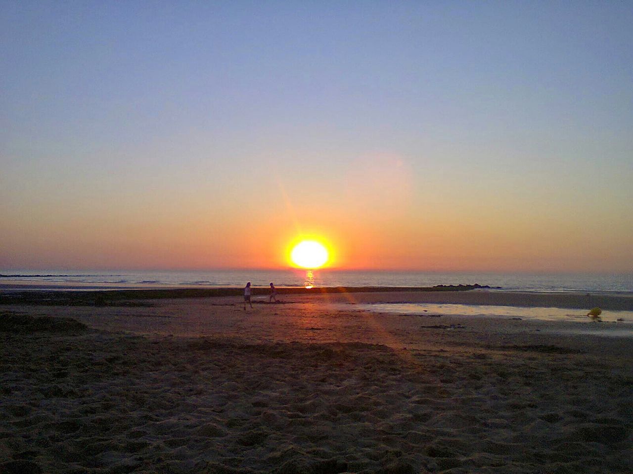 Scenic view of sea against bright sun during sunset