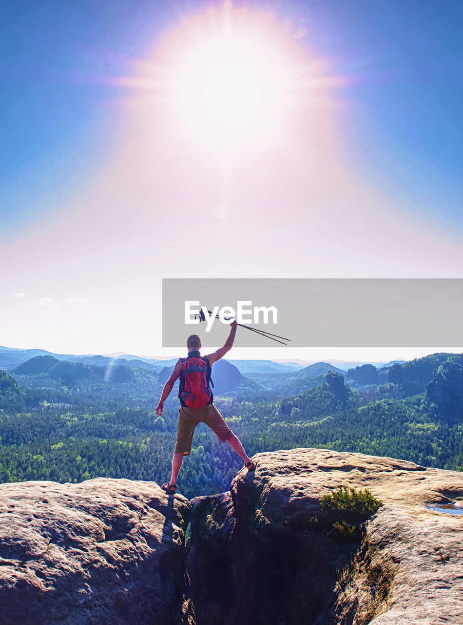 Hiker with poles raising his hands up. man screaming with happiness on a mountain top.