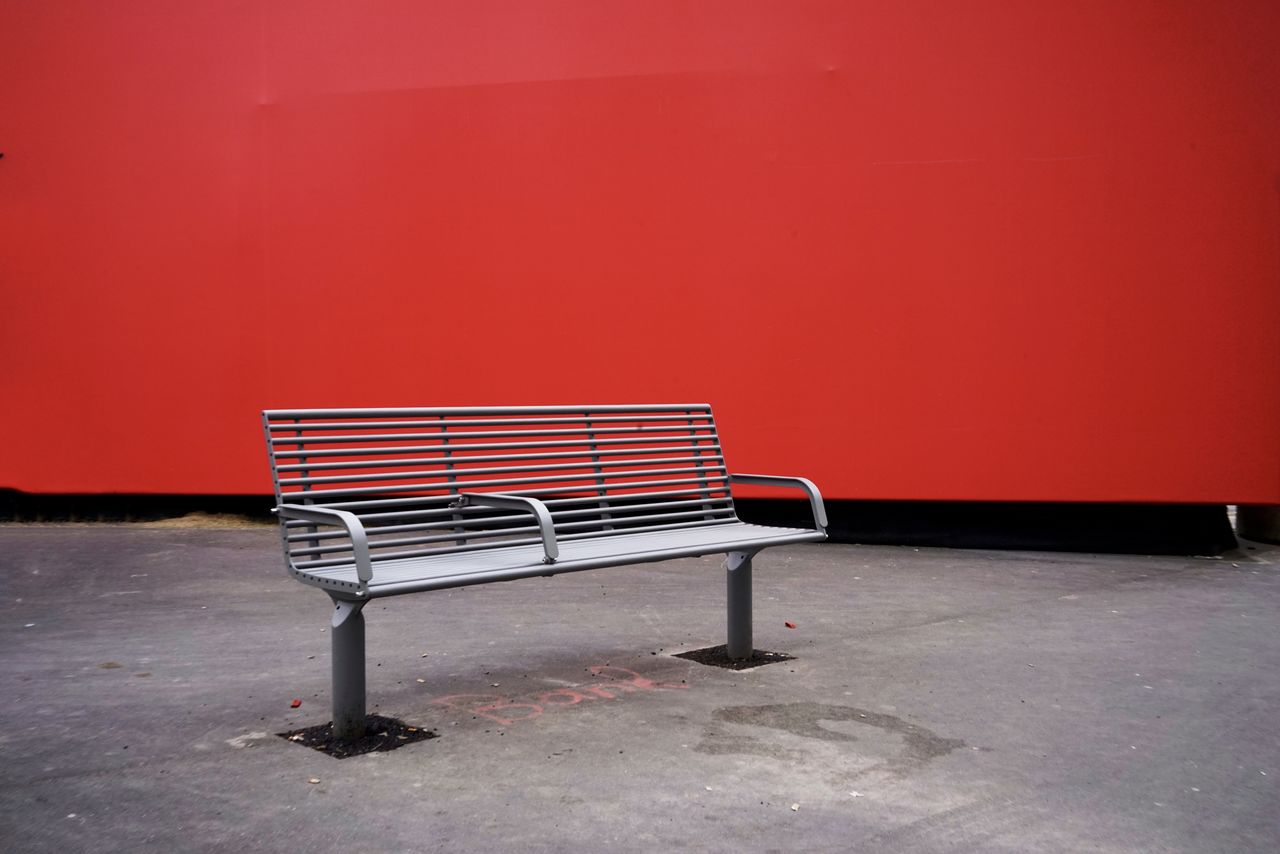 Empty bench against red wall