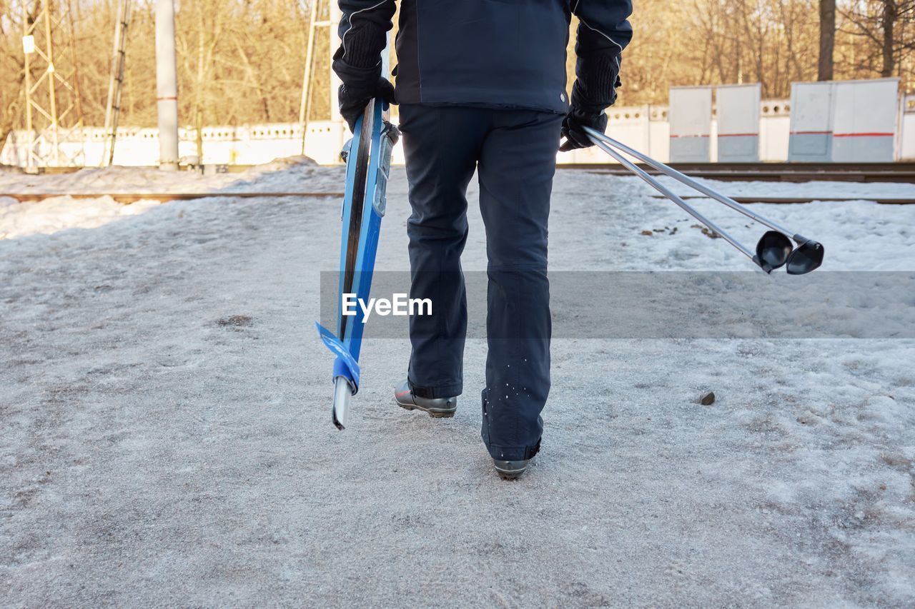 Man goes cross-country skiing to forest in winter. person has skis and sticks in hands