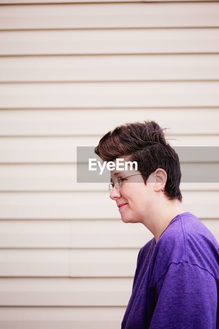 Smiling woman wearing eyeglass against wall