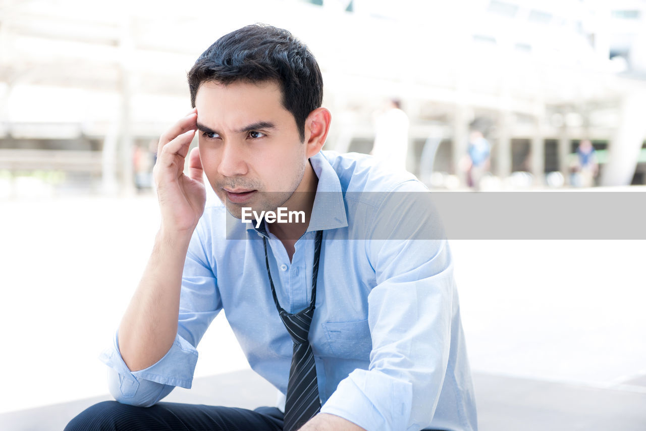Frustrated businessman sitting outdoors