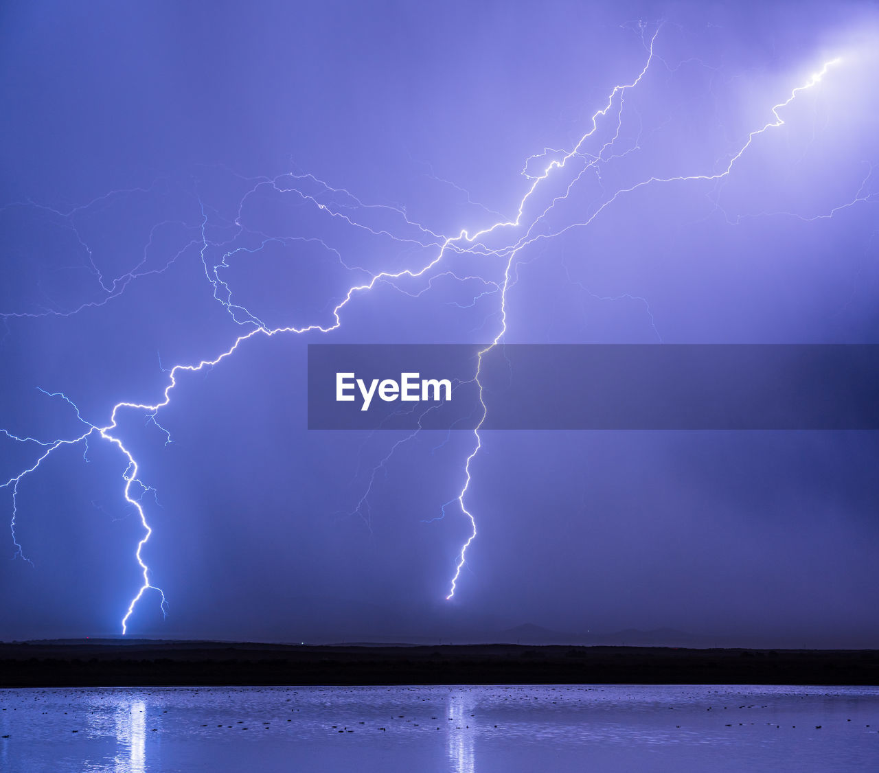 Lightning striking behind a small pond near willcox, arizona