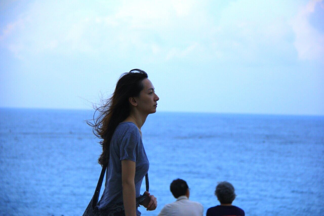 YOUNG WOMAN STANDING AT BEACH