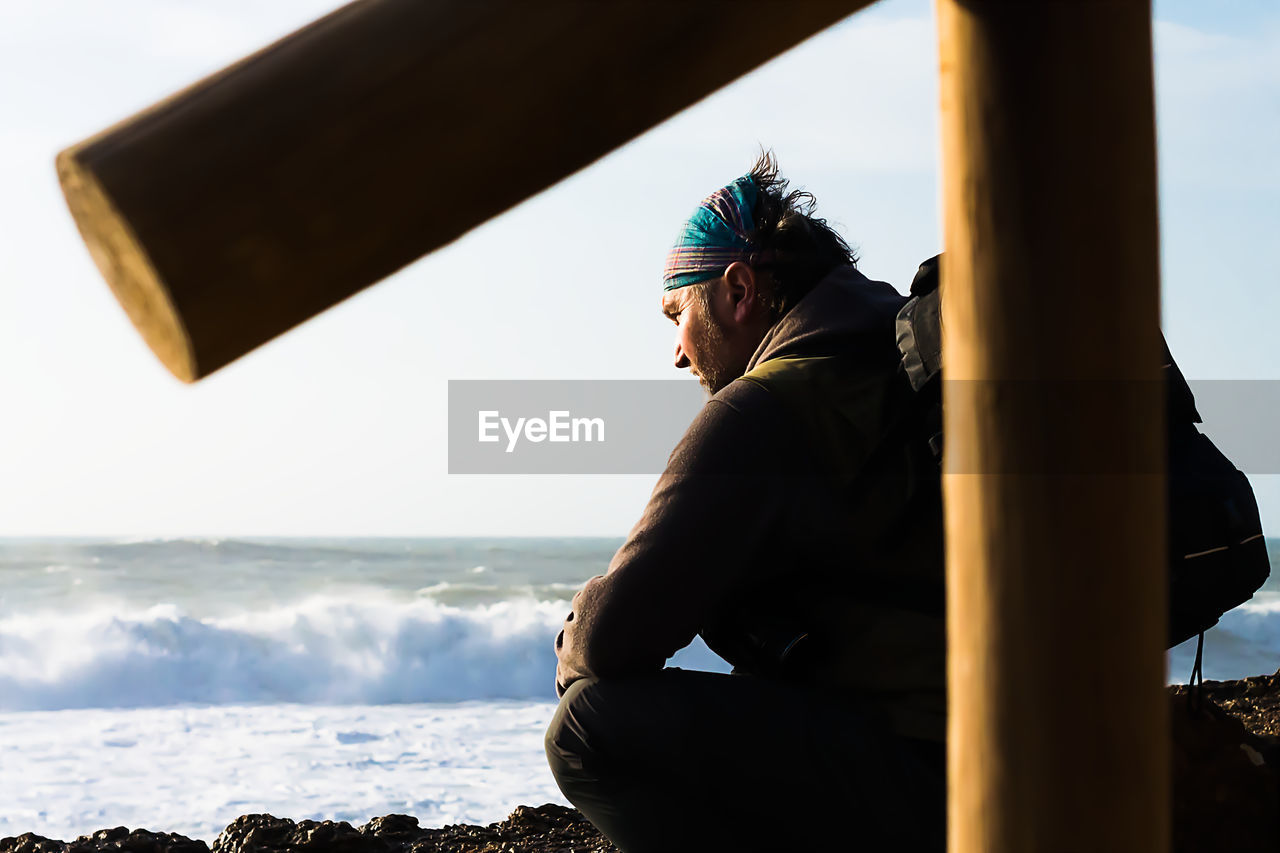 Side view of man sitting on beach