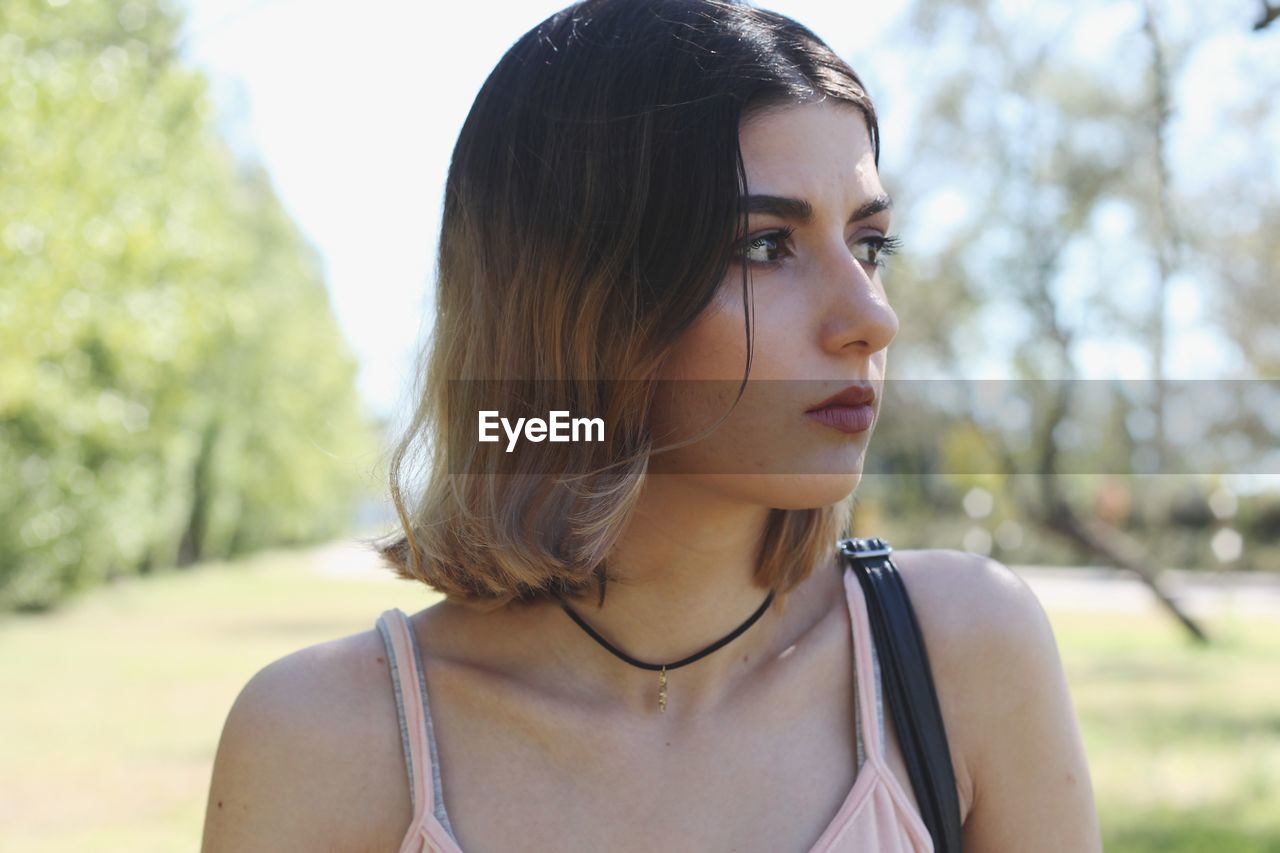 Close-up of thoughtful young woman standing at park