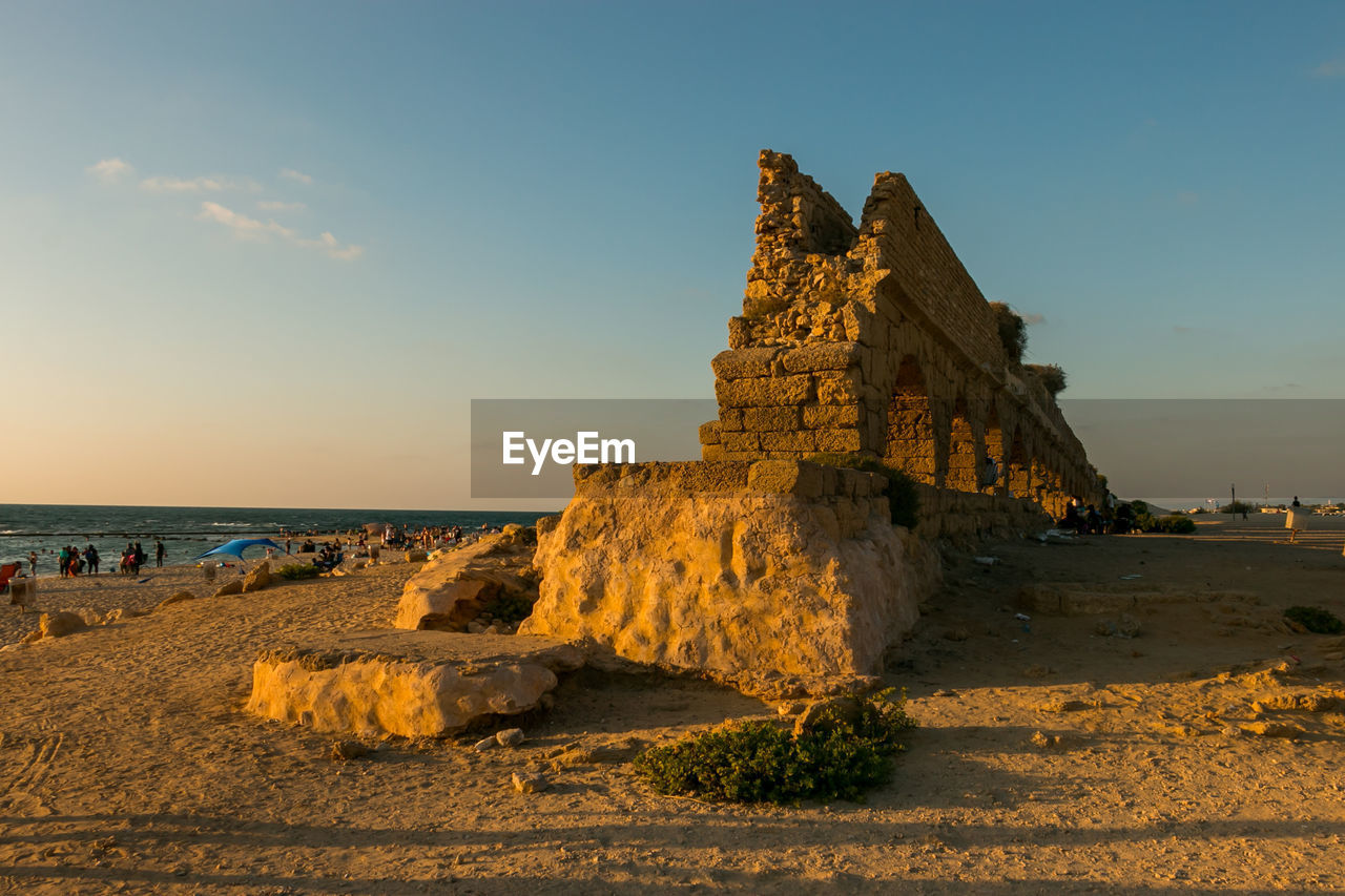 sky, land, sand, rock, sea, nature, beach, travel destinations, water, architecture, history, coast, travel, the past, scenics - nature, sunset, landscape, temple, beauty in nature, built structure, horizon, ocean, tourism, ancient, outdoors, no people, tranquility, cloud, old ruin, sunlight, ancient history, clear sky, tranquil scene, blue, holiday, terrain, tower, shore, building exterior