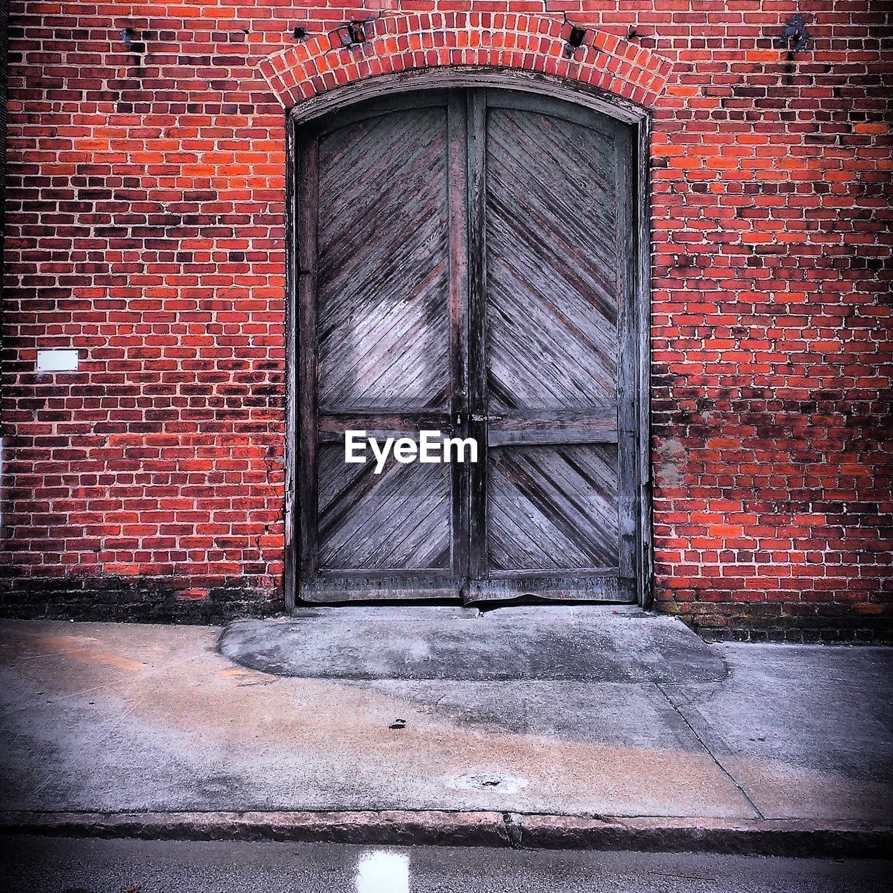 Closed wooden door against brick wall of house