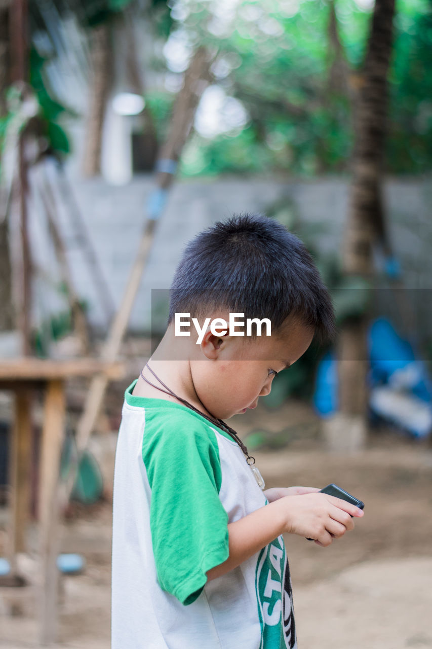 BOY HOLDING MOBILE PHONE AT CAMERA