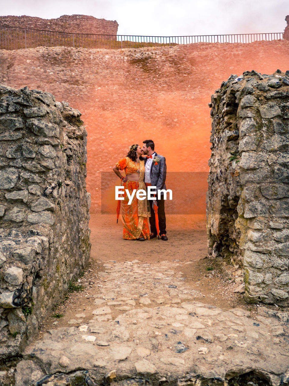 Couple kissing against concrete wall