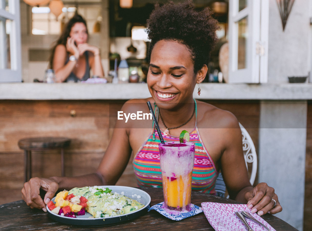 Close-up of young woman having food and drink on table