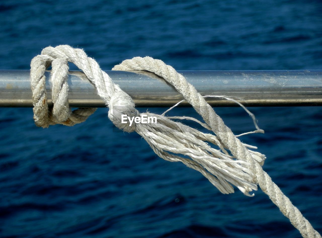 Close-up of rope tied to boat railing against sea