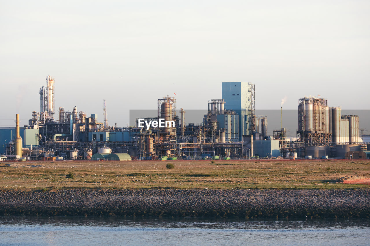 Industrial buildings next to a waterway shipping canal in rotterdam port.