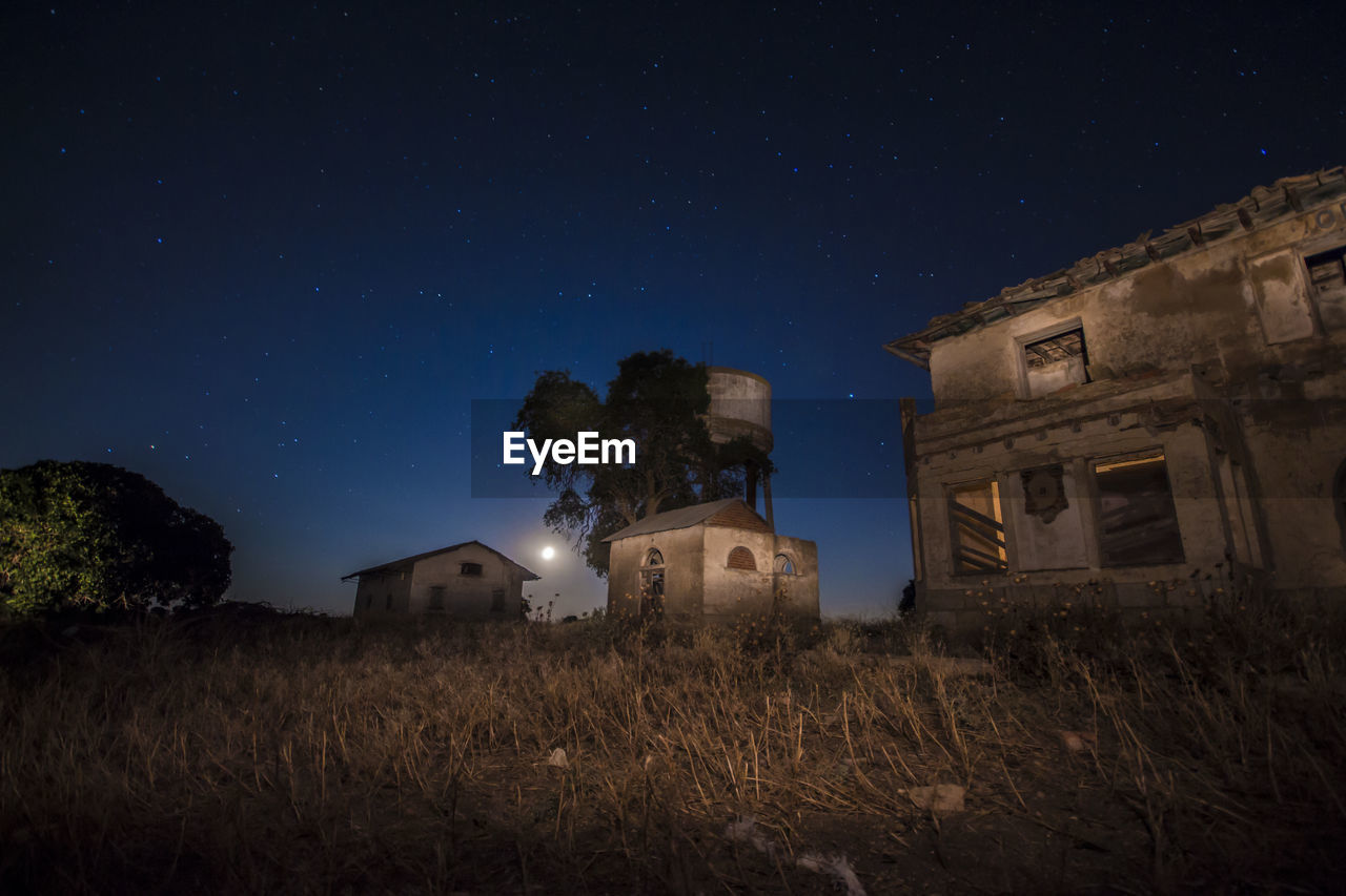 Low angle view of abandoned house on field against sky at night
