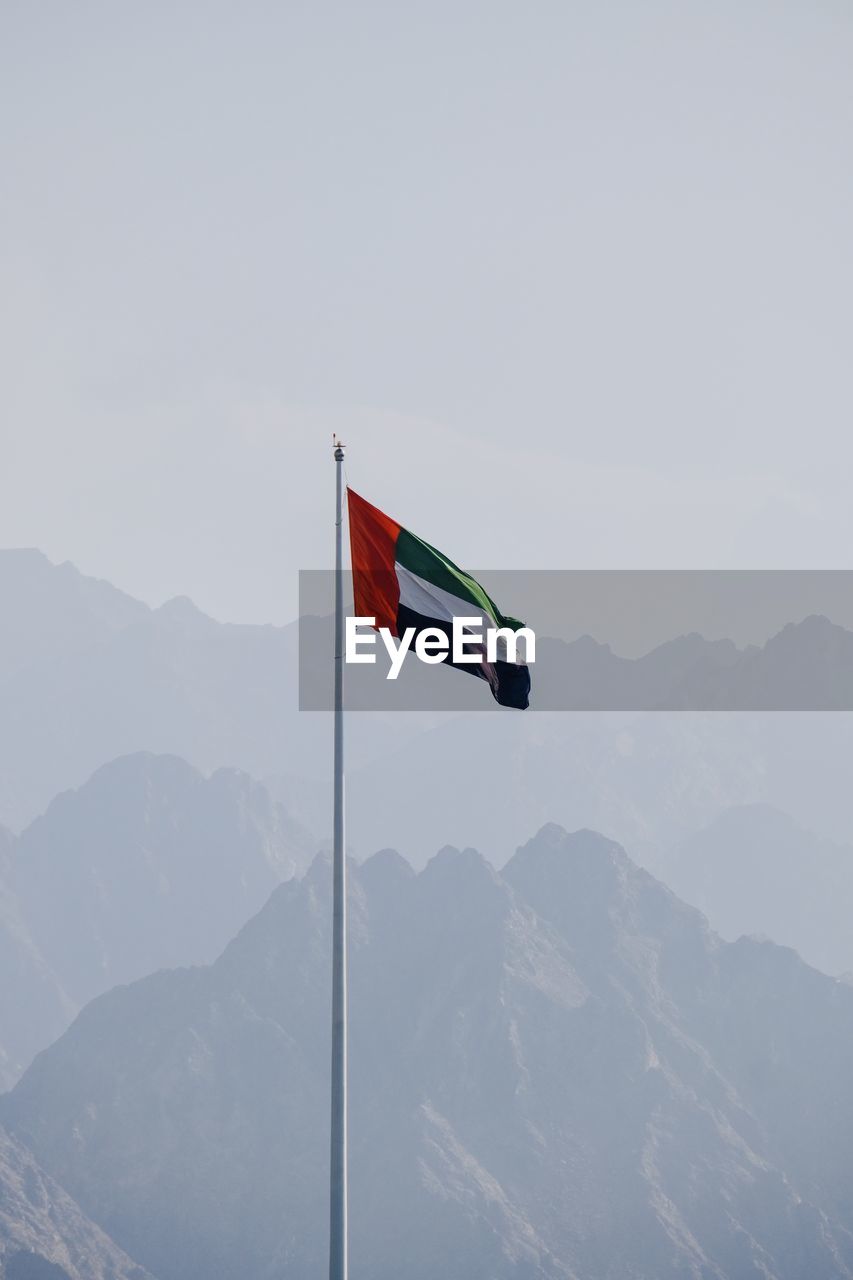 LOW ANGLE VIEW OF FLAGS AGAINST MOUNTAIN RANGE