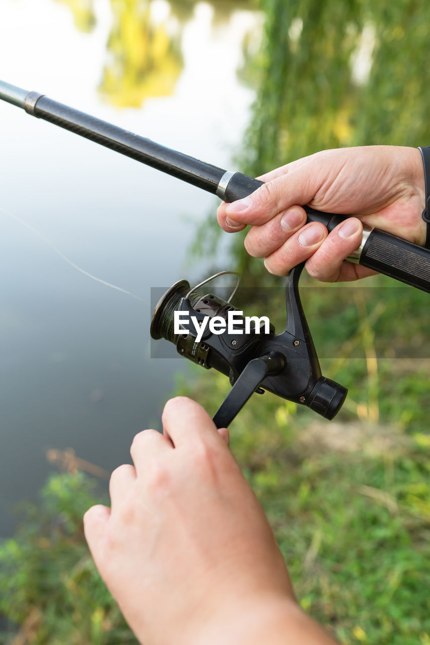 Fishing reel. the guy spins the coil on the background of the lake. 