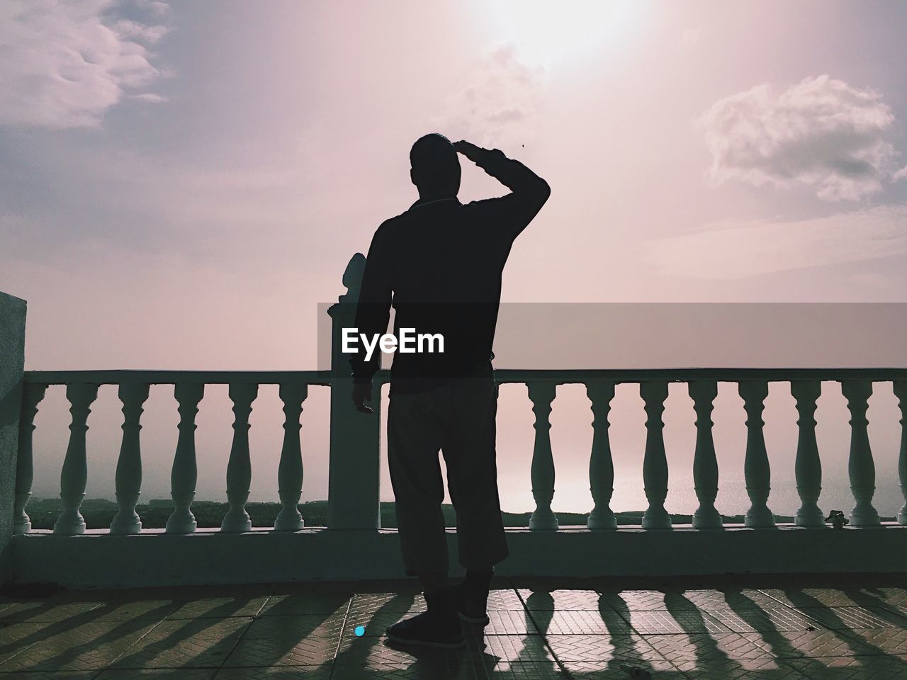 Rear view full length of man standing in balcony against sky